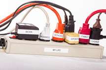 Power strip with labeled plugs depicting a busy life.