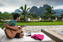 boy child playing a guitar and palm trees 