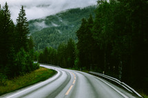 curve on a road through a foggy mountain 