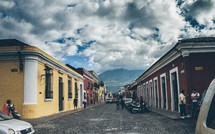 colorful buildings and parked cars along a cobble stone street in Cuba
