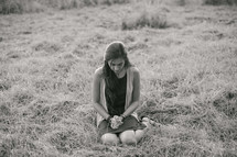 a woman kneeling in grass praying 