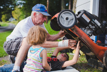 grandfather and his grandchildren fixing a lawnmower 