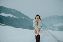 a happy woman standing in the snow 
