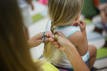 a woman braiding a girls hair 