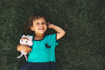 Small girl with stuffed animal in the grass