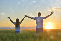 young couple feeling free in a beautiful natural setting, in what field at sunset