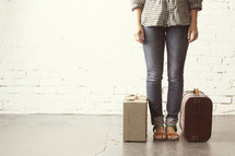 Girl standing ready to go with packed luggage.