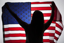silhouette of a woman holding up an American flag.