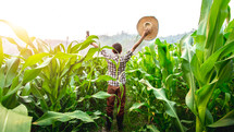 a farmer in a corn field with hands raised 