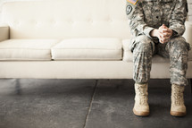 soldier sitting on a couch praying