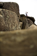 couple hugging standing on top of rocks 