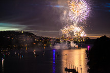 fireworks bursting in the night sky over a bay 
