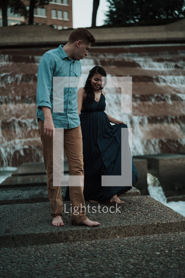 a couple holding hands walking on a fountain 