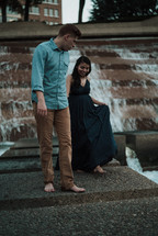 a couple holding hands walking on a fountain 
