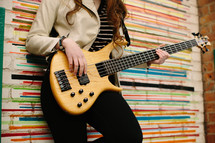 woman learning against a wall holding an electric guitar 