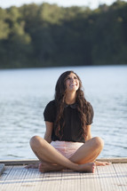 woman sitting on a dock looking up smiling 