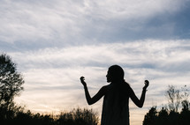 silhouette of a woman with raised hands 