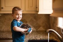 a boy washing dishes in the sink 