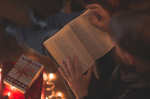 a man sitting on the floor reading a Bible near Christmas gifts 