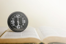 wall clock on an open Bible 