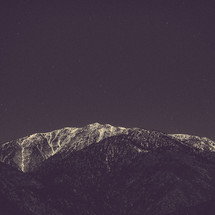 stars in a night sky over a snow covered mountain peak 