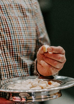 Man holding a communion bread plate.