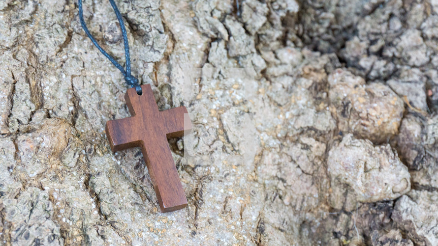 wooden cross necklace on a rock 