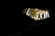 Silhouette of couple walking outside a cave.