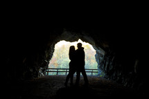 Silhouette of embracing couple standing inside a cave.