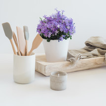 kitchen utensils in a jar, house plant, wood tray, linen fabric, votive candle 