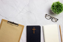 clipboard, Bible, and notebook on a desk 