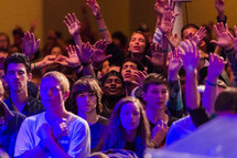 Young people, youth, teenagers in worship with hands lifted, raised hands, singing