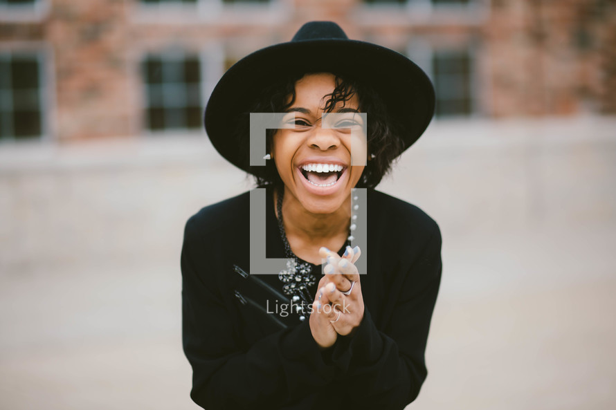 An African American woman in a black hat laughing 