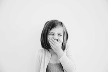 little girl covering her mouth while laughing.