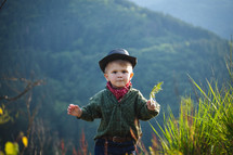 Cute Little Boy with Hat and Bandana in Beautiful Mountains