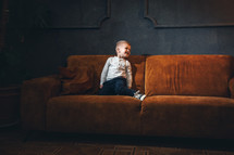 Adorable Little Cute Boy on Vintage Sofa in Dark Interior
