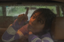 a girl touching rain drops on a car window 