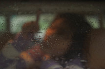 a girl touching rain drops through a car window 