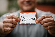 man holding a name badge with the word volunteer 