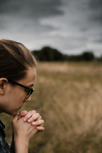 a woman praying in a field 