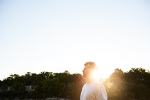 a man standing outdoors and a sunburst 