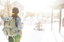 Woman with backpack facing a snow-covered day.