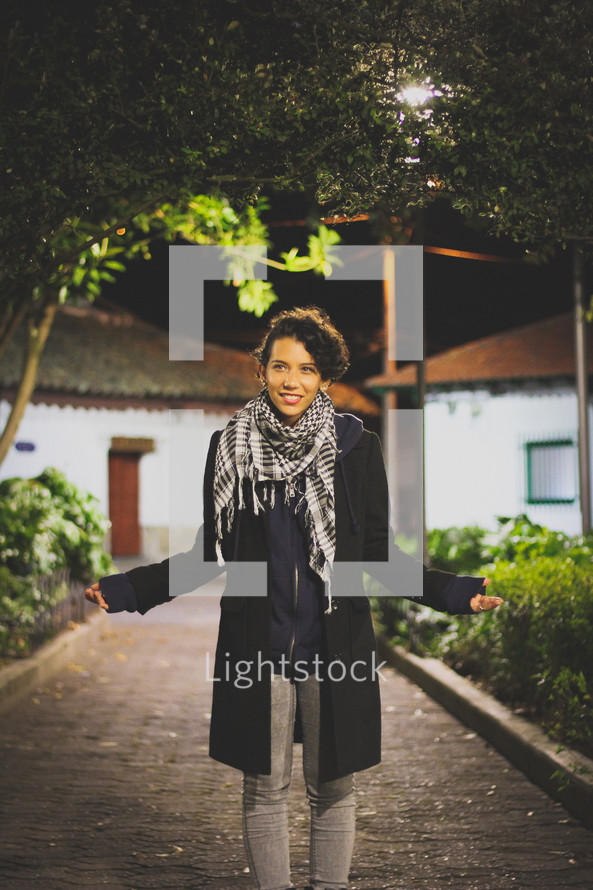 woman standing under a street lamp at night 