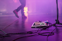 Feet on a stage with a microphone and foot pedal.