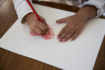 a girl child coloring a heart 