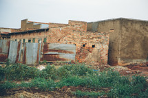 a metal fence and buildings in an African village 