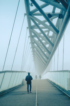 people crossing a foggy bridge in winter 