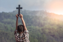 a boy holding up a cross outdoors 