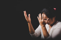 Asian woman with hands raised in prayer