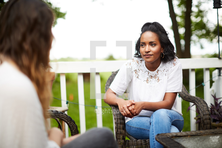 women talking together sitting on a patio outdoors 